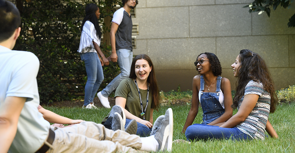 Graduate students sit outside in the grass.