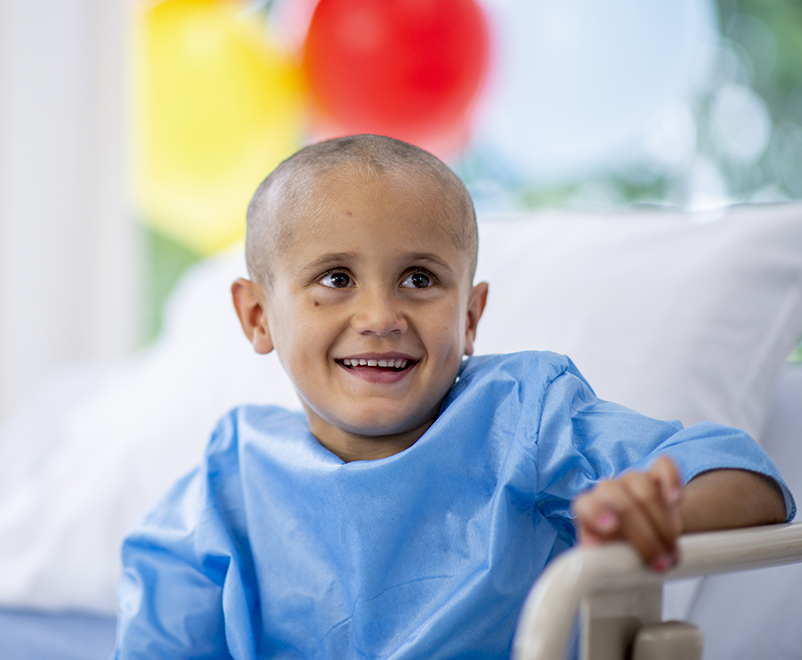 boy with cancer smiling in hospital bed
