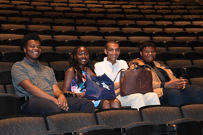 Four teens sitting in a row of seats