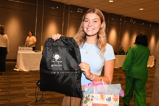 Young woman holding up a Johns Hopkins branded bag