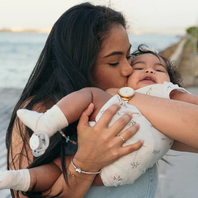 A woman holds and kisses her baby