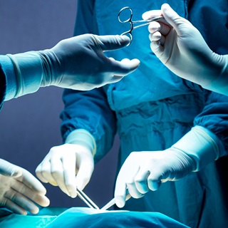 A surgeon is offered a pair of scissors during a surgery.