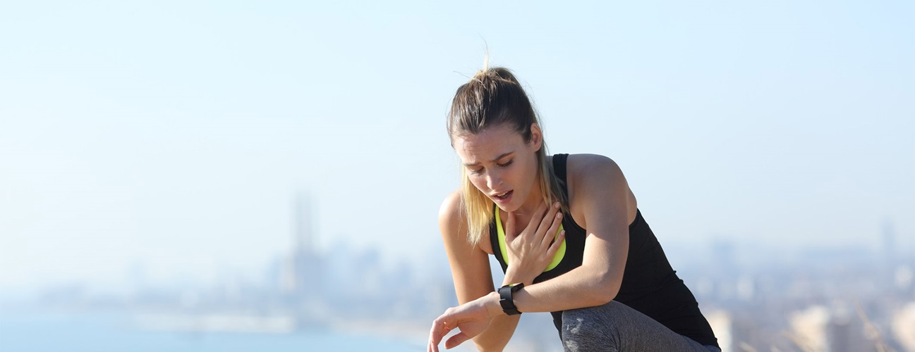A woman struggling to breathe on her run. 