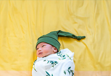 A newborn baby lying on a yellow sheet.