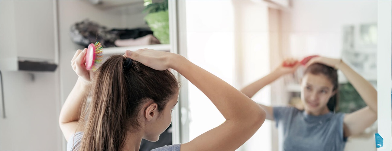 A teen girl brushes her hair as she experiences precocious puberty