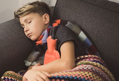 A boy with symptoms of iron deficiency anemia in children rests on the couch