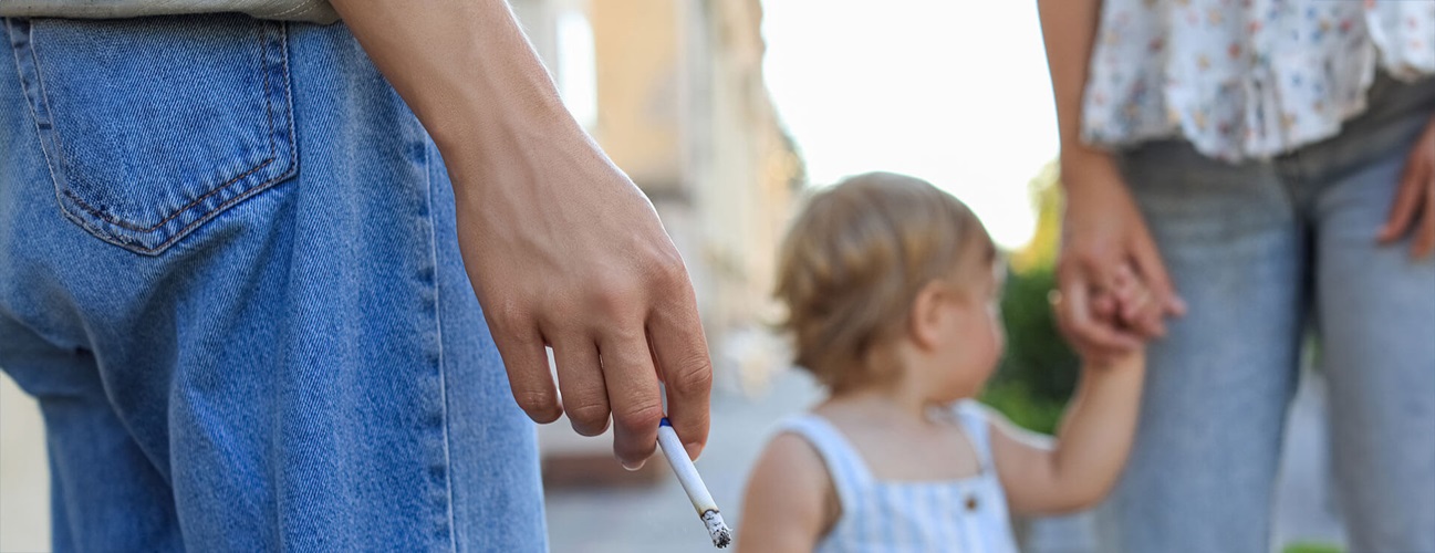 A man holds a cigarette as he considers the impact of thirdhand smoke on kids