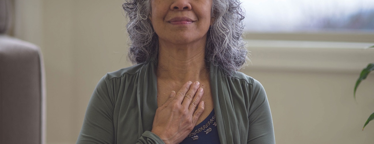 an older woman inhaling with her hand on her chest