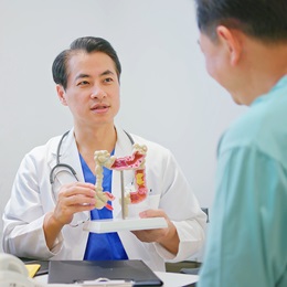 Doctor showing a patient a model of a colon.