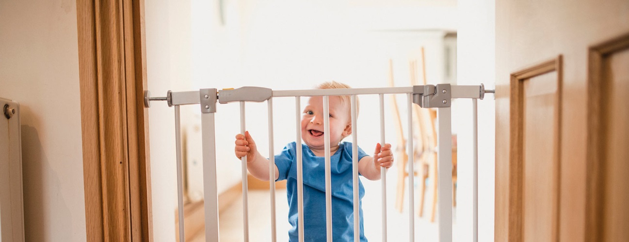 Baby safely behind a baby gate installed at home