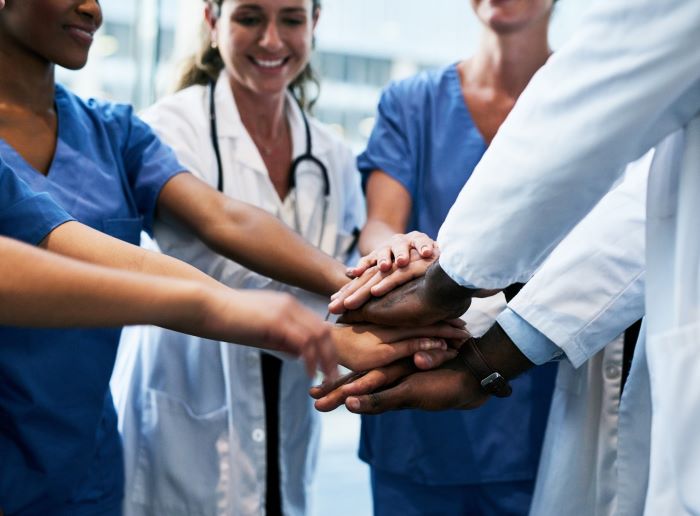 Doctors standing in a circle placing all of their hands in the middle