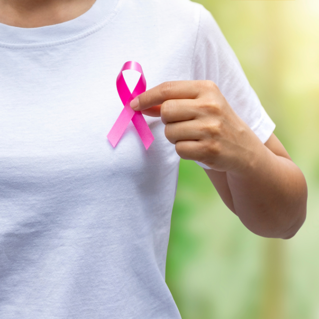 Women wearing a white shirt holding a breast cancer ribbon