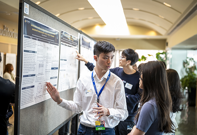 Male and female discussing poster on a board in front of them.
