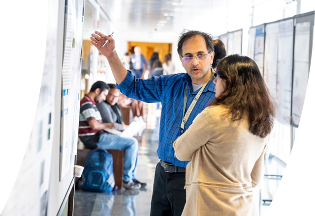Man pointing to and discussing a poster on a board.