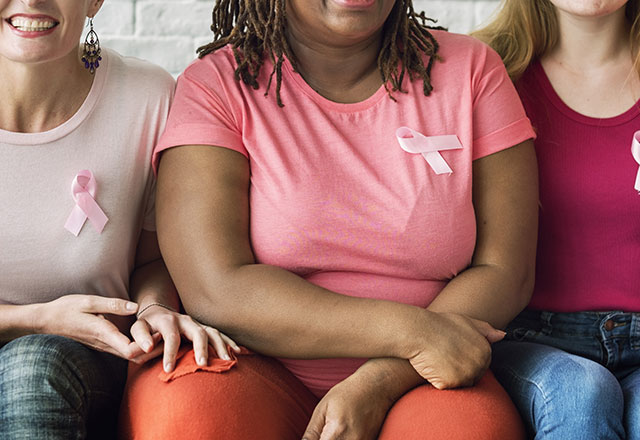 women sitting next to each other with pink ribbons on their t-shirts