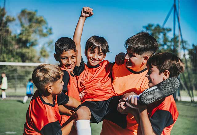 kids holding each other up after winning game