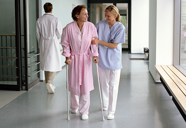 woman helping a patient walk in the hallway