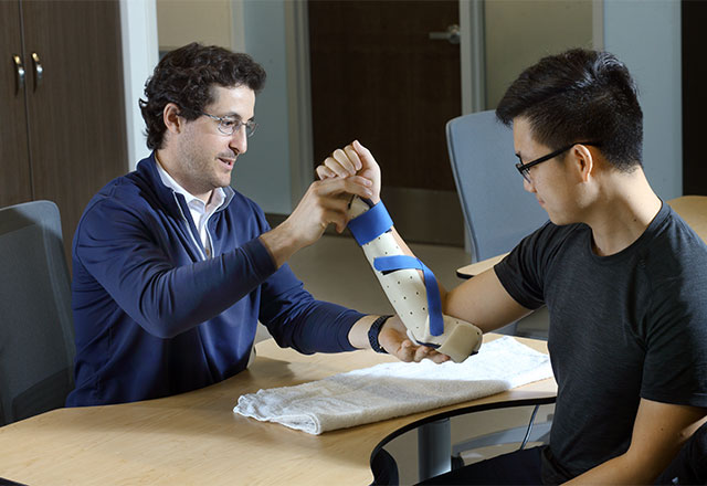 Healthcare provider fabrication an upper extremity orthotic with a patient.