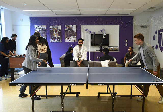 Students playing ping pong in their Cap college room. 