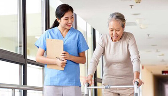 A nurse assists a woman with a walker.