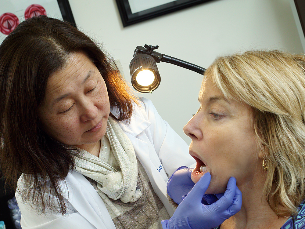 Physiciian examines a patient's jaw and mouth.
