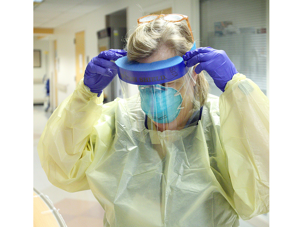 Staffer wearing a face shield, mask, gown and gloves