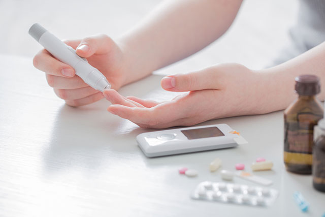 Close up of patient self-administering blood sugar test.