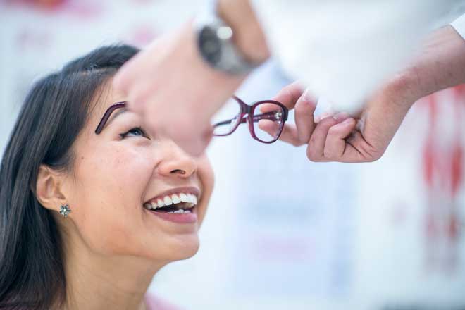 a young woman tries on glasses at the optical shop