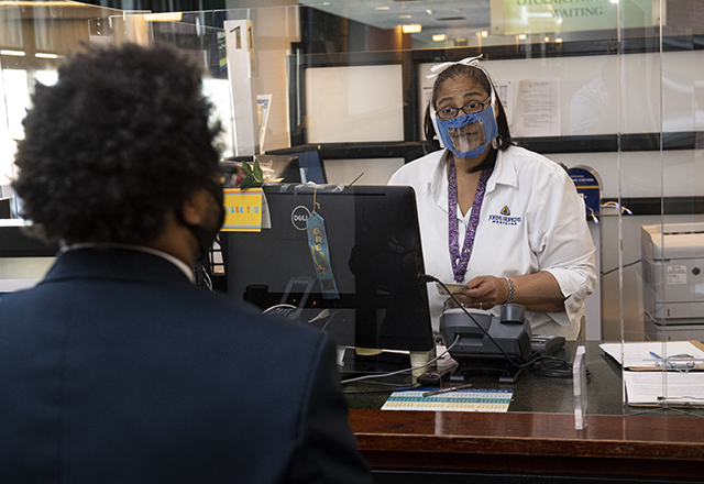 staff wearing plastic face mask while talking to patient