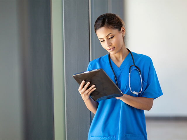 physician holding clipboard and wearing stethoscope 