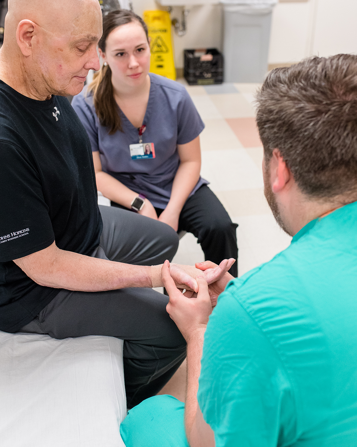 A physical therapist and student work with a patient.