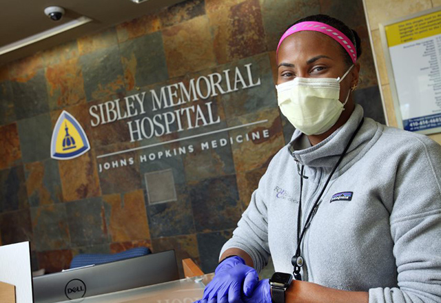 Lynne Lightfoote stands in front of Johns Hopkins Sibley Memorial Hospital